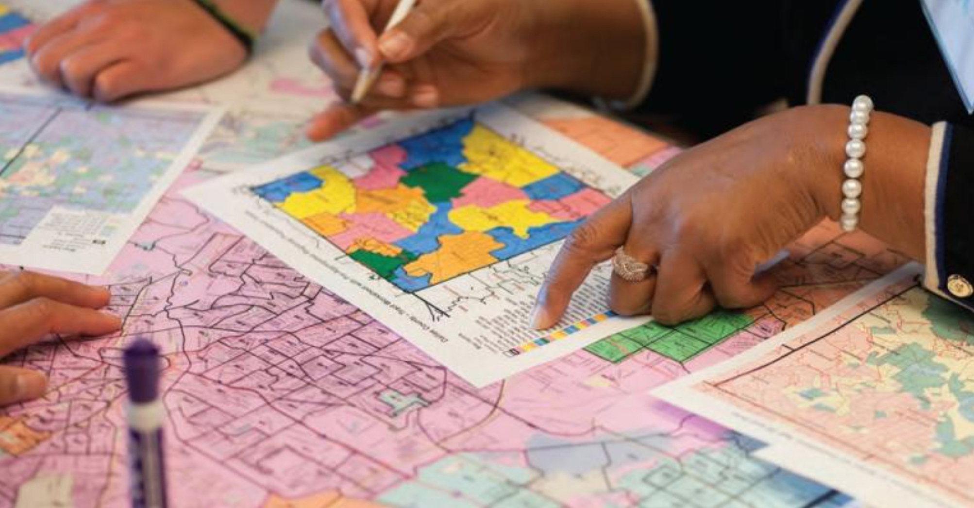 Image of people evaluating districts on maps; courtesy League of Women Voters of California Education Fund