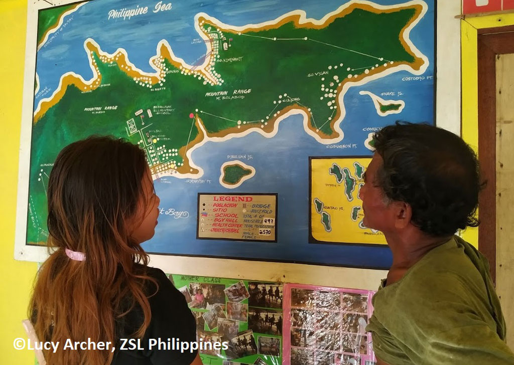 Photo of researchers studying a map of the Philippines where pangolins are natively found by Lucy Archer, ZSL Philippines