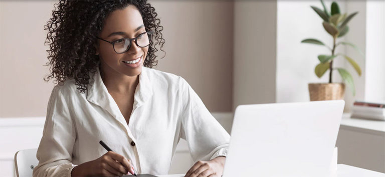 African-American woman looking at laptop with pen in hand