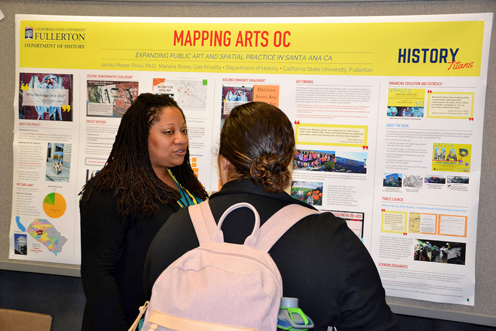 Students discuss a poster presentation on expanding public art and spatial practice in Santa Ana, CA, during the AAG annual meeting.