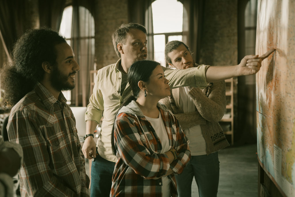 Diverse group of four people studying map as one person points at a position