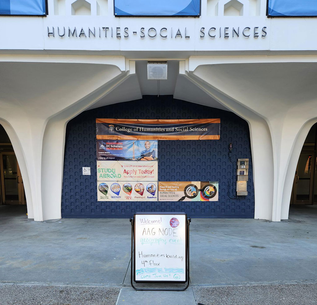 A directional sign welcomes attendees to the Humanities and Social Sciences building during the California State University, Fullerton AAG 2023 node events.