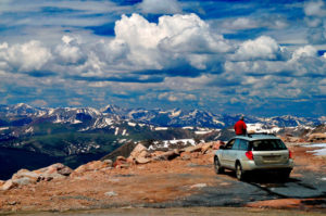 Photo of an SUV parked at the edge of a cliff overlooking Mount Evans in Colorado