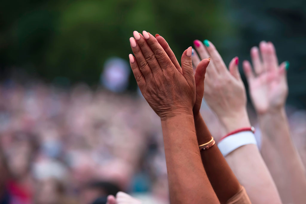 Image showing social justice and peaceful protesting racial injustice. Black and white hands together against the background of a blurred crowd of people.