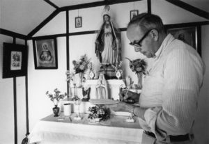 Photo of William Laatsch taking notes near an alter with religious artifacts