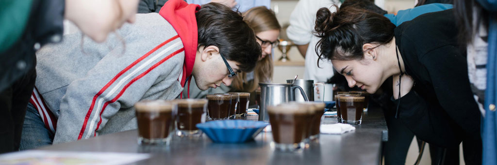 A group of students explores geography with using their sense of smell over drinking glasses filled with liquid.