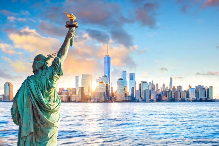 View of Statue of Liberty from back overlooking New York city skyline at sunset