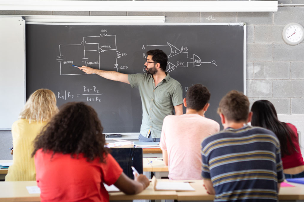 Professor explaining concepts written on a whiteboard to students.