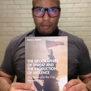 Rasul Mowatt holds his book "The Geographies of Threat and the Production of Violence."
