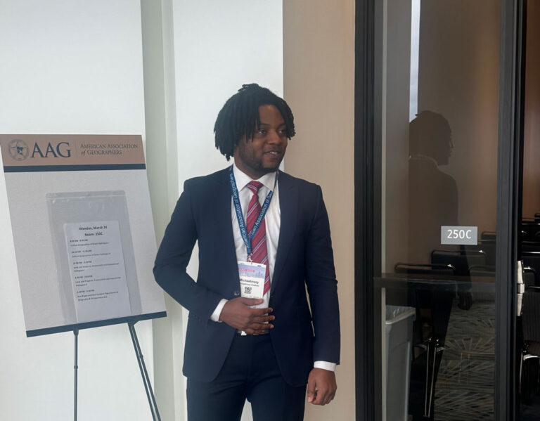 Michaelmary Chukwu poses next to a session board outside of a session room.