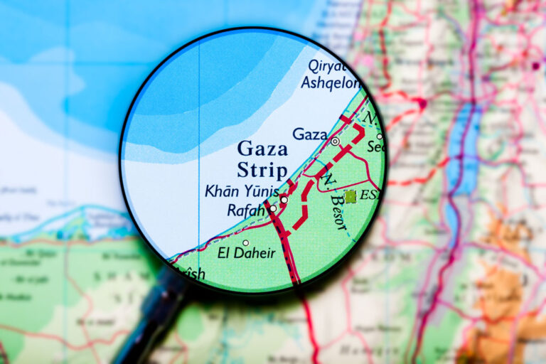 Magnifying glass highlighting Gaza on a larger map.