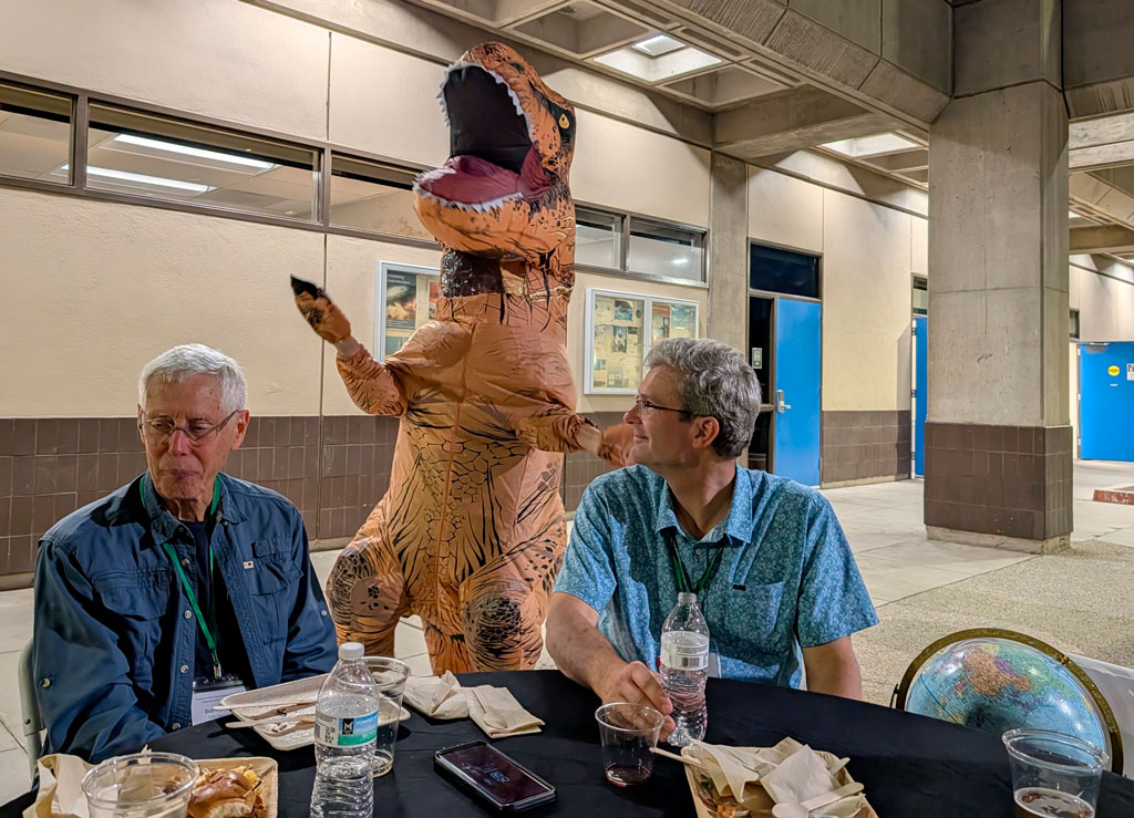 An person dressed in a dinosaur costume entertains attendees at the APCG regional division meeting