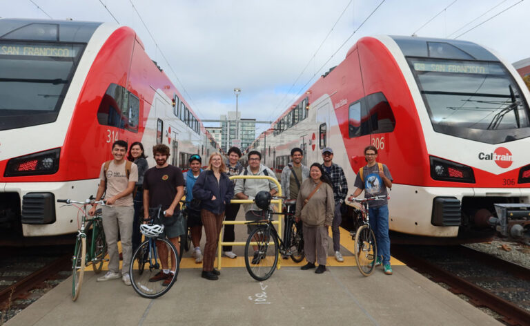 San Francisco State University students gather between two CalTrains for a transportation class field trip.
