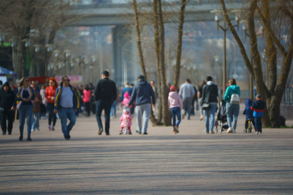 A diverse group of eople walking in a park area in the city