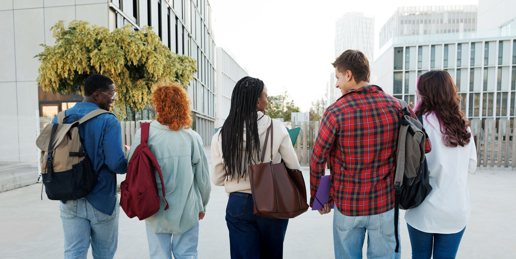 Multi-ethnic group of students walking away on campus after class, going back home or to dormitory