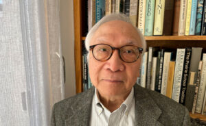 James Chan posed in front of a wall shelf full of books