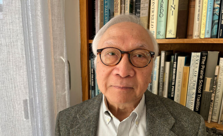 James Chan posed in front of a wall shelf full of books