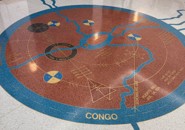 The tiles are brown, teal, gold and black forming a circle that illustrates a map of rivers and shapes in the Congo.